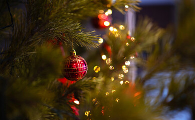 Decorated Christmas tree on blurred background. Christmas decoration balls hanging on pine branches christmas tree garland and ornaments with abstract background with copy space. Selective focus.