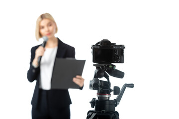 blurred anchorwoman with microphone and clipboard near digital camera isolated on white