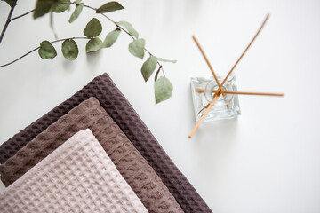 expensive luxury towels in beige and brown tones on a white background, glass aroma diffuser. photo in light colors. cleanliness and relaxation.