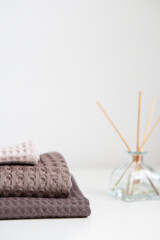 expensive luxury towels in beige and brown tones on a white background, glass aroma diffuser. photo in light colors. cleanliness and relaxation.