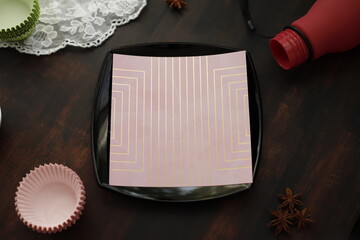 Serwetka we wzorki na czarnym talerzu kwadratowym na brązowym stole drewnianym