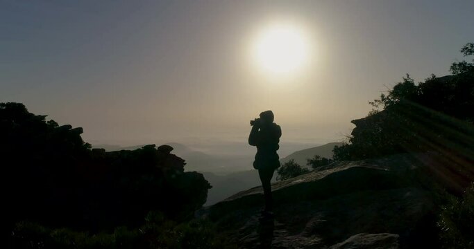 Mujer aventurera con mochila haciendo fotos en la cima de monta&ntilde;a al atardecer
