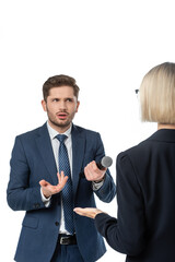 discouraged journalist with microphone gesturing near blonde businesswoman during interview isolated on white