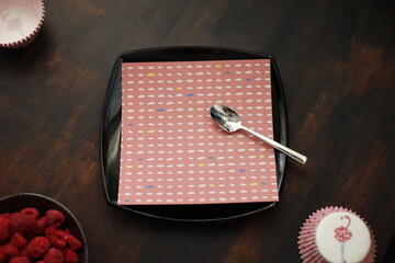 Serwetka we wzorki na czarnym talerzu kwadratowym na brązowym stole drewnianym