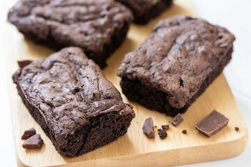 Top view of chocolate brownies on wooden board on white table, homemade sweet and dessert concept
