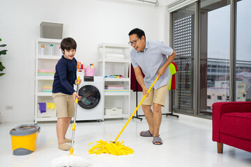 Happy family cleans the room. Asian father and son do the cleaning in the house. A young man and...