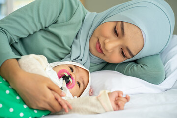 Obraz na płótnie Canvas Asian Muslim new born baby wearing HIJAB with mother sleeping on white bed