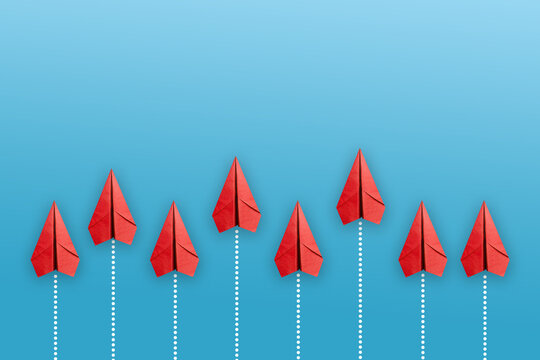 Leadership concept with red paper plane leading among white on blue background