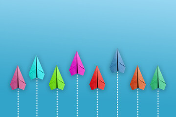 Group of white paper plane in one direction and one red paper plane pointing in different way on blue background. 