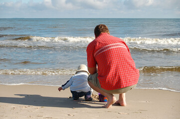 Familie mit Kleinkind am Sandstrand spielend