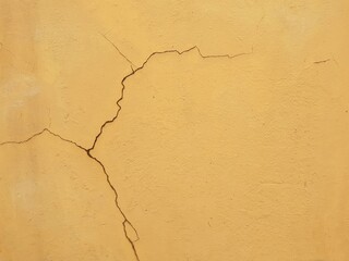 Cracks on the orange plaster wall.
