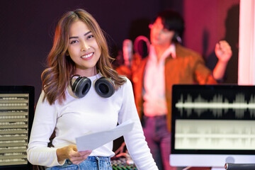 Asian producer woman in white shirt standing by the sound mixing console. Happy female music...