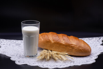 Composition of glass of milk, wheat, white bread on a white tablecloth