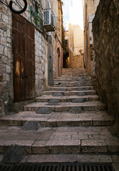 Fototapeta na wymiar Empty stone paved alley in Old Town Jerusalem, staircase and old buildings