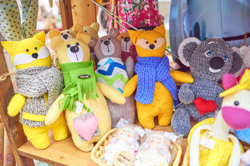 Colored handmade toys cats and teddy bears, yellow, brown, orange, in a green, blue and gray scarf. Russian text: handmade