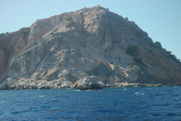 Fototapeta na wymiar Blue sea and rocky cliff on sky background. Rocky island in the Mediterranean sea.