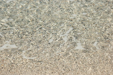 Sea bottom with small stone pebbles in crystal clear water. Small pebbles and sand seabed background.