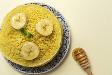 Homemade traditional moroccan baghrir with honey, strawberries and mint from above
