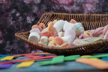 Fototapeta na wymiar Multicolor marshmallow and jellybeans mix in a rustic basket
