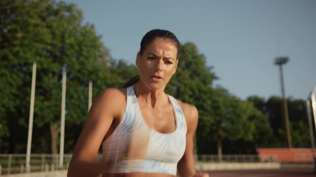 Beautiful Female Athlete in Light Blue Sports Top Running Extremely Fast in an Outdoors Stadium