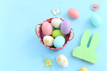 Cute bunny next to easter colorful eggs over pastel background