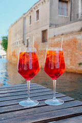 Two glasses of Spritz Veneziano cocktail served near the Venetian canal.  Popular italian summer aperitif drink. Venice background.