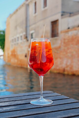 Glass of refreshing Aperol Spritz cocktail served on the deck bar in Venice. Traditional venetian aperitif drink.