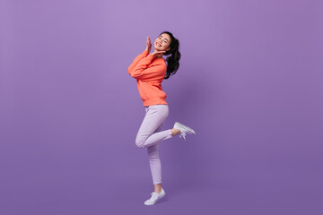 Refined asian woman standing on one leg. Full length view of blissful chinese girl dancing on purple background. - Powered by Adobe