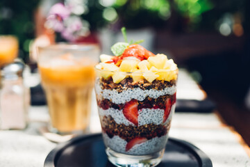Greek yogurt with homemade granola, fresh berries and fruits on wooden background in a glass on a wooden table.Yogurt and chia parfaits. Healthy foods providing probiotics. Selective focus.