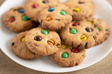 Cookies with colorful M&Ms chocolates close-up on a white plate.
