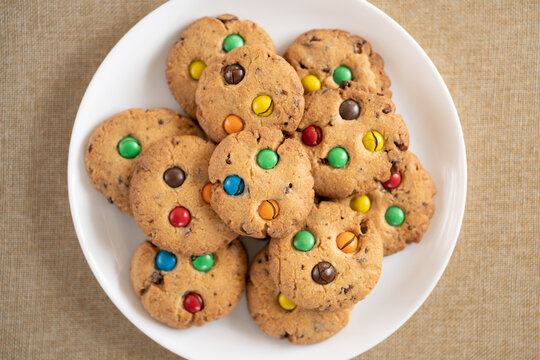 Cookies with colorful M&Ms chocolates close-up on a white ceramic plate.