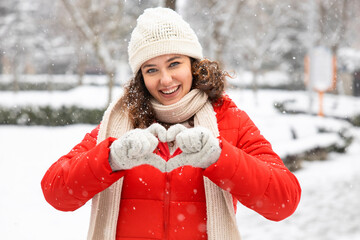 Young woman make heart shape with hands in winter gloves..