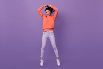 Cheerful korean girl jumping on purple background. Studio shot of attractive asian woman dancing with smile.