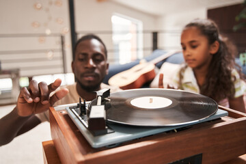 Man listening music on vinyl records with his daughters - Powered by Adobe