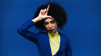 African american woman showing loser sign isolated on blue
