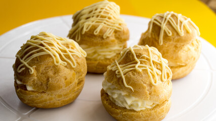 Choux Cream Puff Custard Whipped Cream Filling on a wooden plate