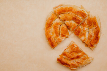 Big chelsea bun with cheese. background for a bakery. large round bun cut into 4 pieces on a brown background. Copy space