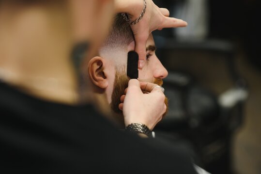 Close up image of barber shaving a man with a sharp steel razor.