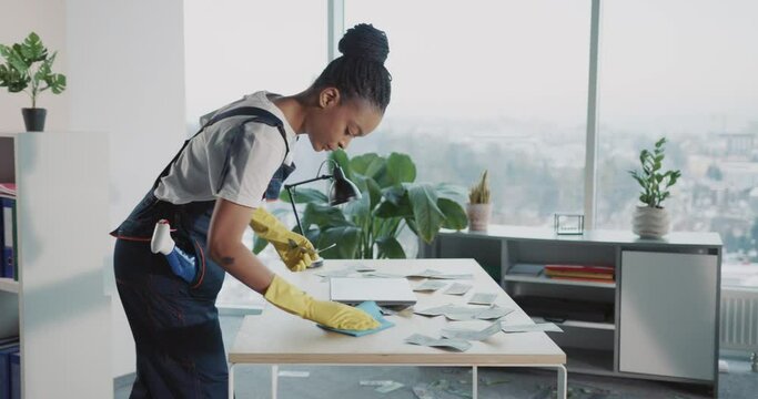 Young african woman and caucasian man workers cleaning services disinfecting corporate office workplace. Woman stealing money collecting banknotes into pocket.