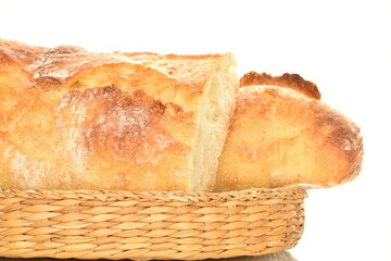 Two halves of a delicious freshly baked French baguette in a straw bowl, close-up, isolated on white.