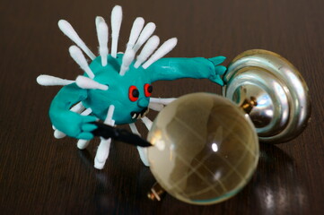 Fototapeta premium Figure of a virus with a toy knife. Next to it is a small glass globe.