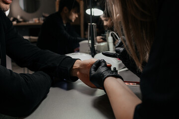 Men's manicure. Design of men's manicure. The master makes a man manicure. The concept of professional nail care. Close-up of the manicurist's hands at work. A man does a manicure.