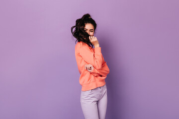 Funny asian woman in casual attire playing with hair. Studio shot of wonderful korean girl isolated on purple background.