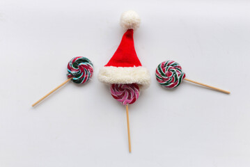 The candies on the white background.On the top of one candy is small Santa hat. High quality photo