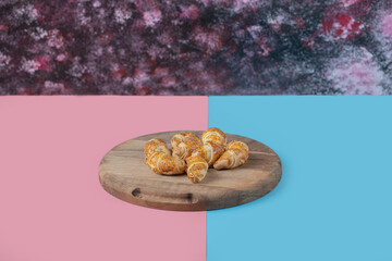 Fried caucasian mutaki cookies on a wooden board on pink blue background