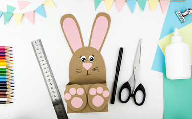 The concept of crafts with children for the Easter holiday. Step-by-step instructions for making craft paper bunny boxes. Step 6 is the finished result.