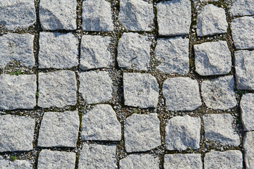 background - fragment of an old sidewalk paved with granite paving stones