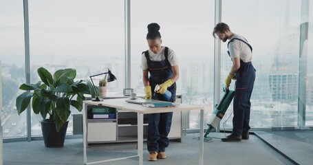 Multi-ethnic cleaning services team couple of african woman and caucasian man cleaning corporate office disinfecting room. Vacuum cleaner.