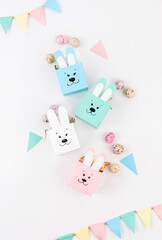 Crafts with children for Easter from colored paper. Boxes bunnies for sweets in the form of eggs. Flat lay.