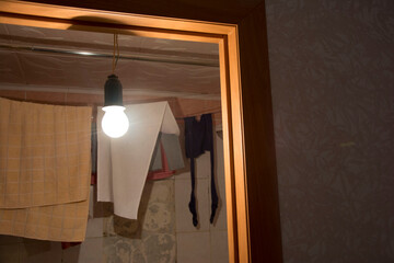 Fototapeta na wymiar Hanging single Incandescent light bulb in an old bathroom